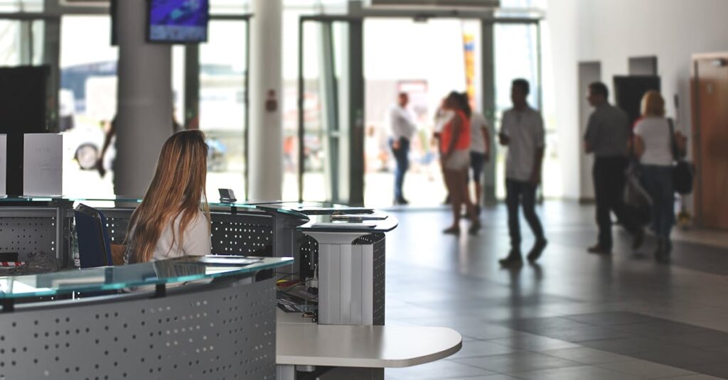 A bustling office reception area with people walking and a receptionist at a modern desk.